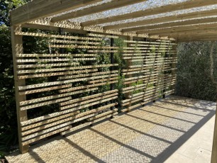 Pergola minimaliste en bois avec mur contemporain et couverture treillis de camouflage à Plascassier (Alpes maritimes, 06)